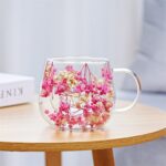 Pink pressed flower double wall glass mug on table