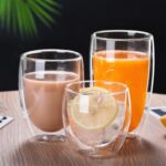 Three clear double wall glasses with cocoa, juice and lemon