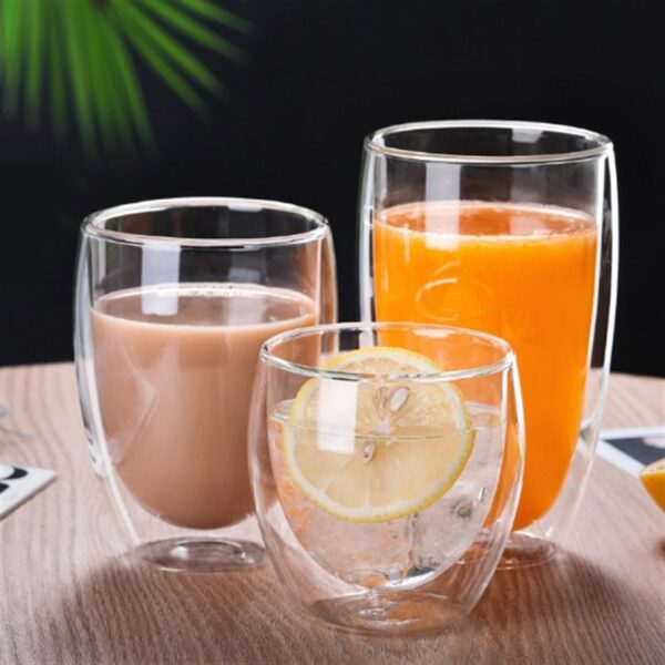 Three clear double wall glasses with cocoa, juice and lemon