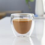 Latte in a clear double wall glass cup on white table