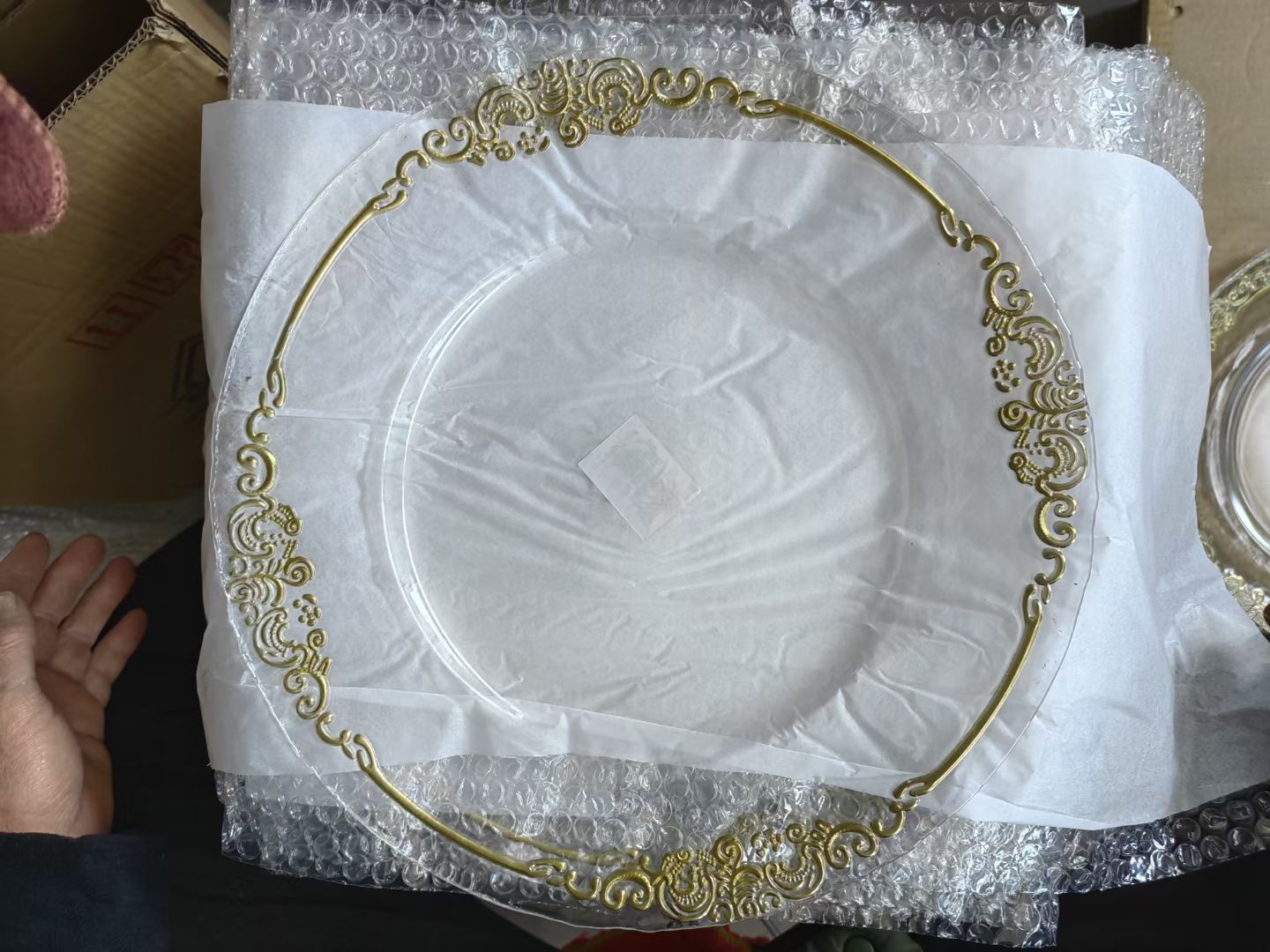 Gold pattern glass charger plates wrapped in bubble wrap before packing