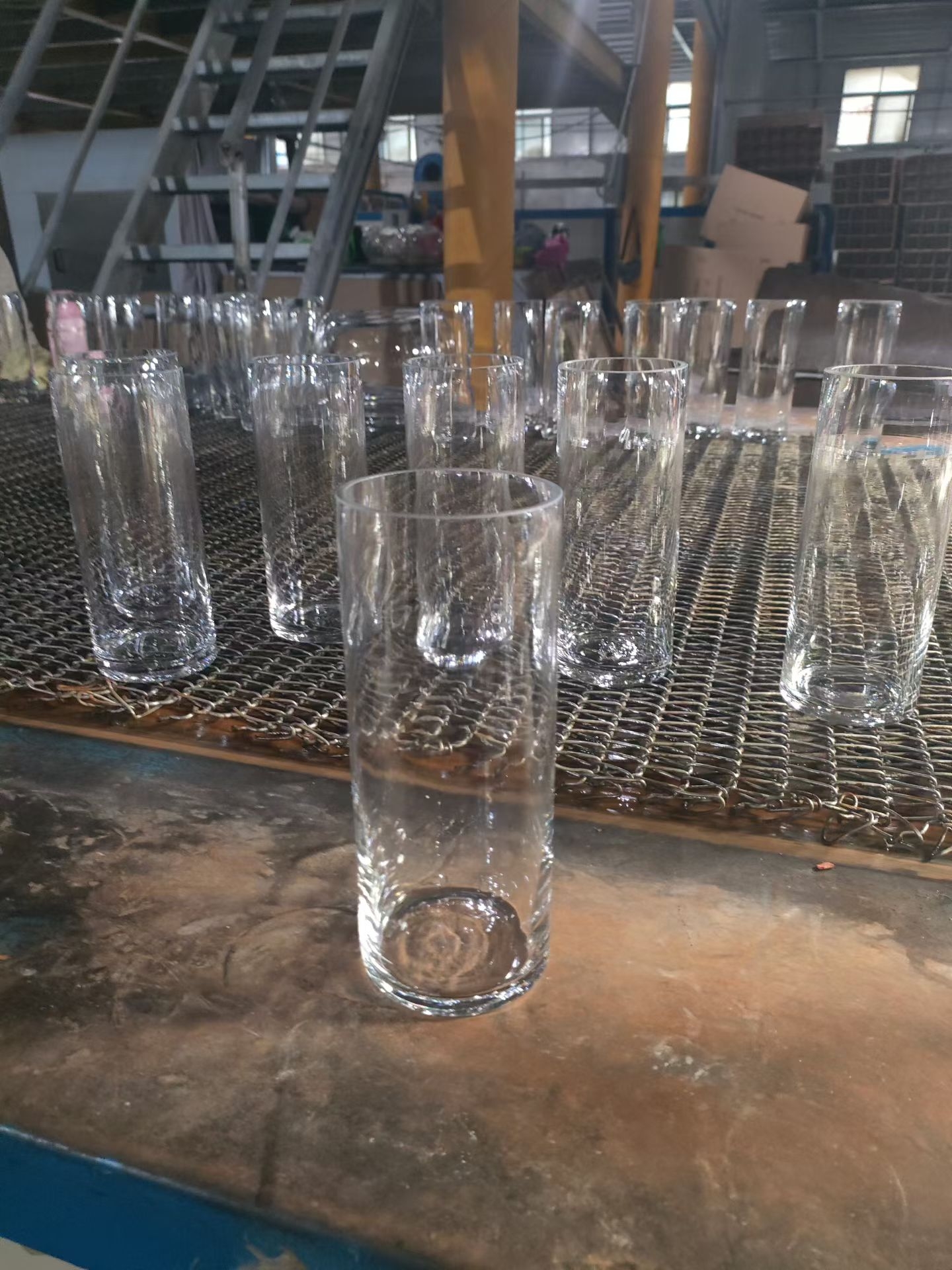 Clear textured handmade glass cylinder vases on the production line
