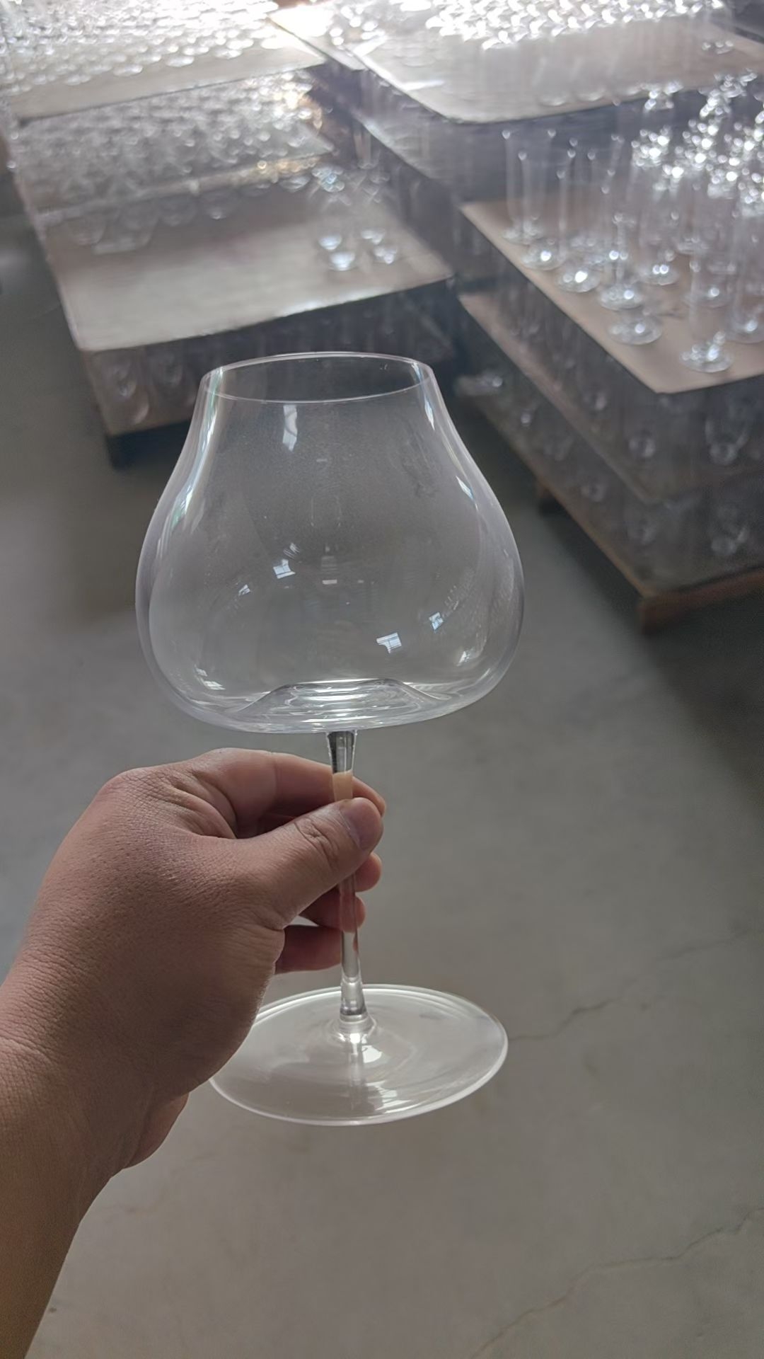 Handmade clear glass brandy balloon snifter held in workshop