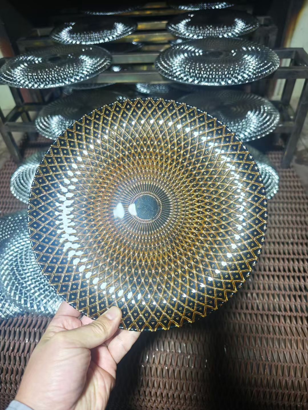 Iridescent silver sunburst 13 inch glass charger plate held in the workshop