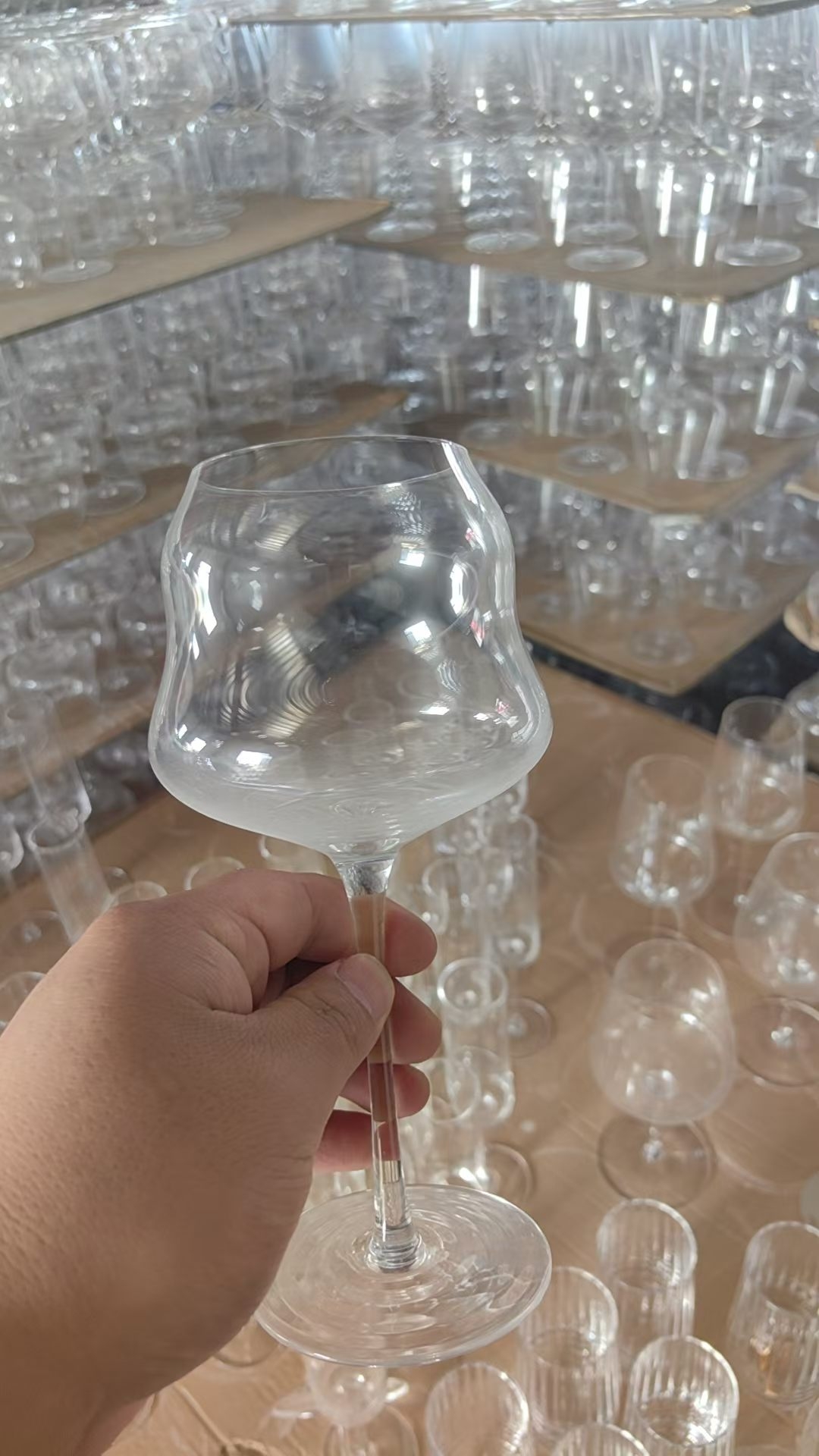 Handmade clear glass white wine goblet held in workshop