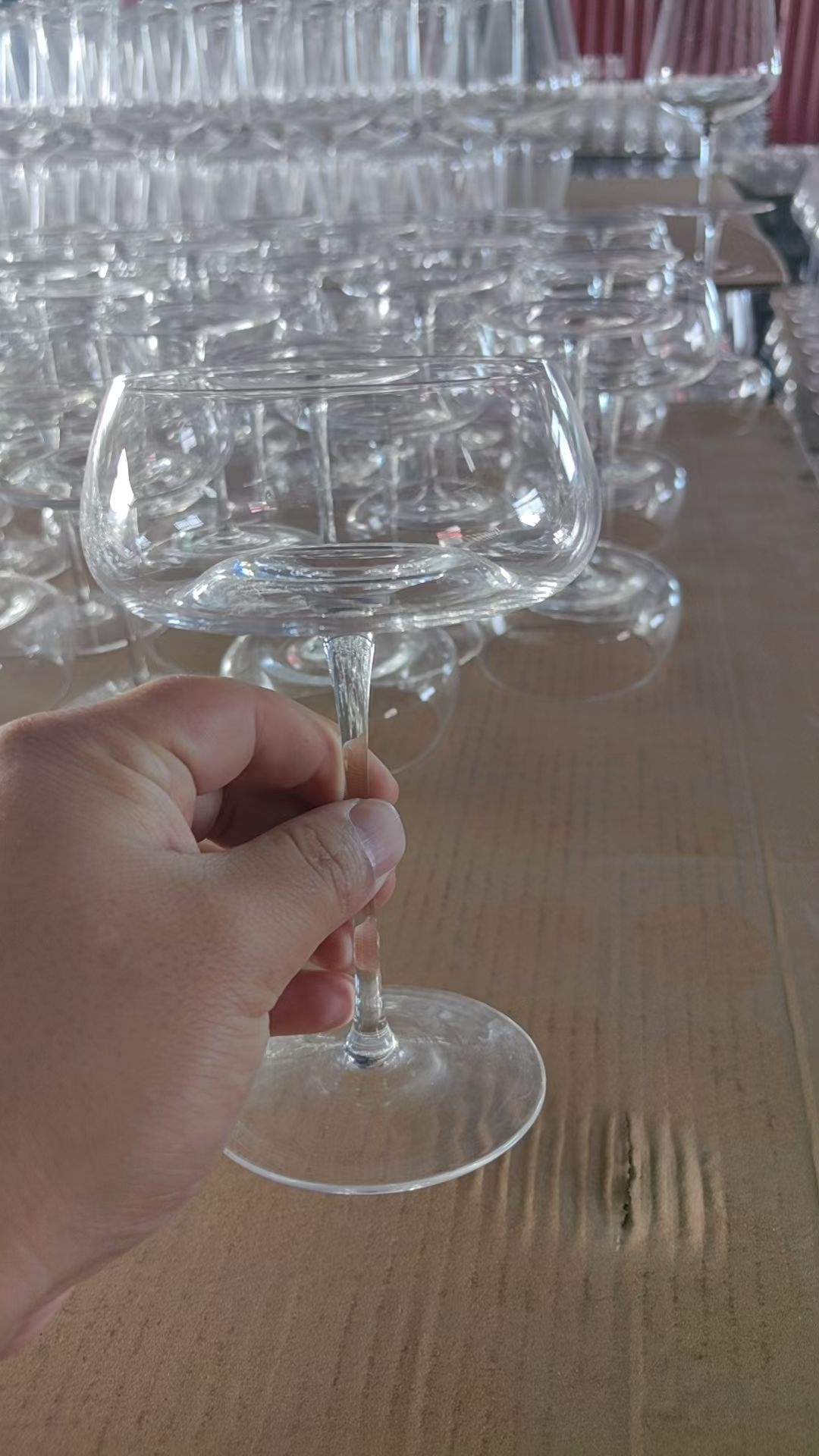 Handmade clear glass champagne flute held in workshop