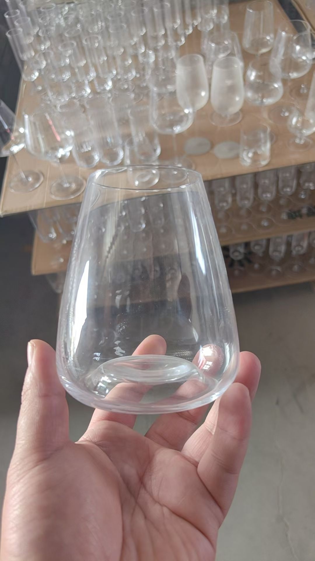 Handmade clear glass stemless tumbler held in workshop